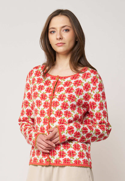 Frau trägt Strickjacke, Modell Juliana, mit rotem Blumenmuster auf hellem Grund vor neutralem Hintergrund