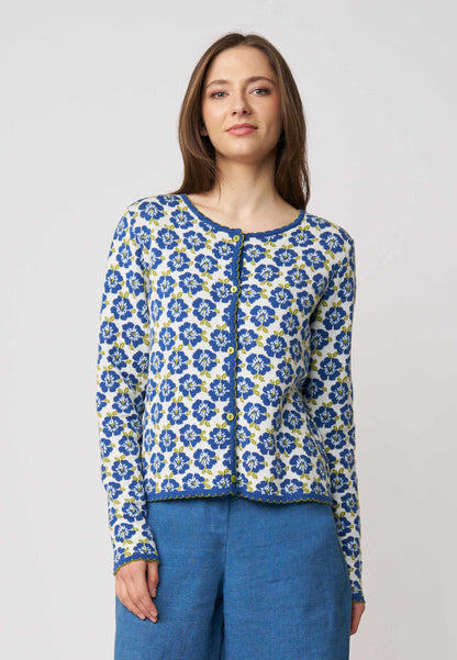 Frau trägt Strickjacke, Modell Juliana, mit blauem Blumenmuster auf weißem Grund vor hellem Hintergrund