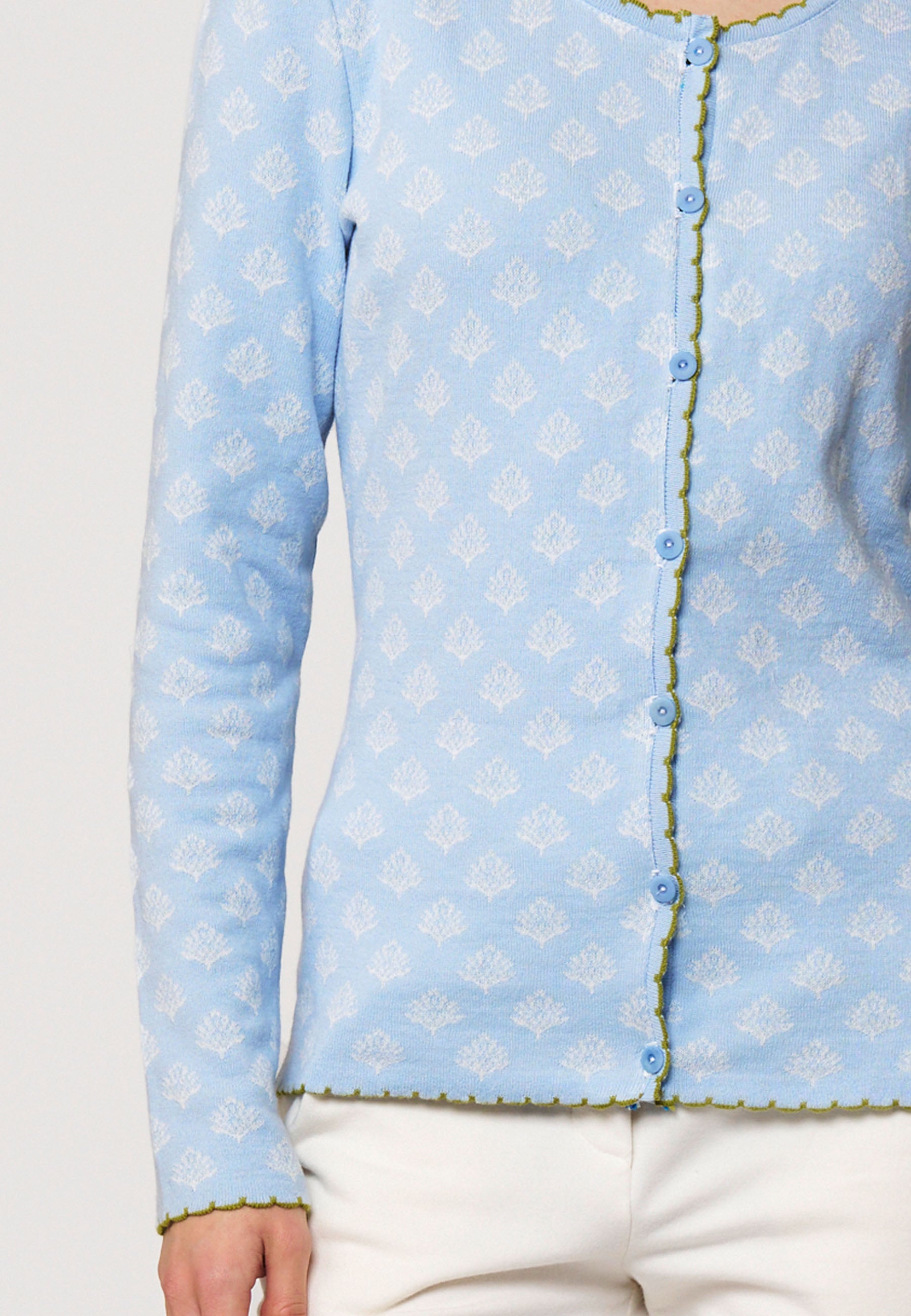 Strickjacke, Modell Lena in zartem Hellblau mit feinem weißem Muster und grünem Zierabschluss, teilansicht getragen
