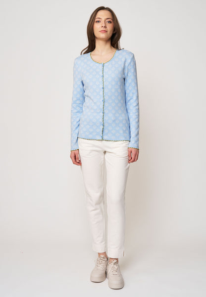 Strickjacke, Modell Lena in Hellblau mit feinem, weißem Muster und grünem, gerüschtem Rand, frontale Ansicht getragen