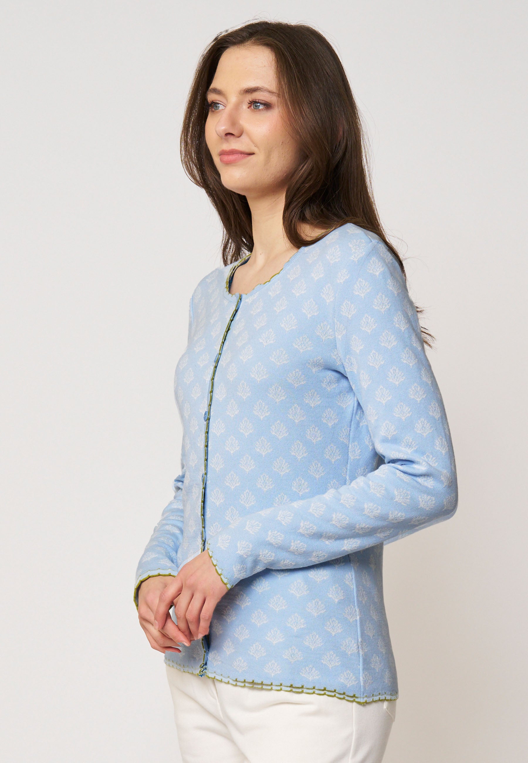 Strickjacke, Modell Lena in Hellblau mit zartem weißen Blattmuster und grünem Zierabschluss, seitliche Ansicht getragen