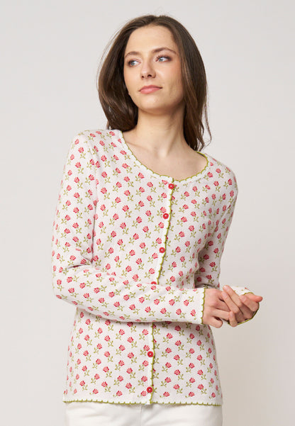 Frau trägt Strickjacke, Modell Lena, in hellem Ecru mit kleinem rosa Blumenmuster und grünem Zierstreifen frontal