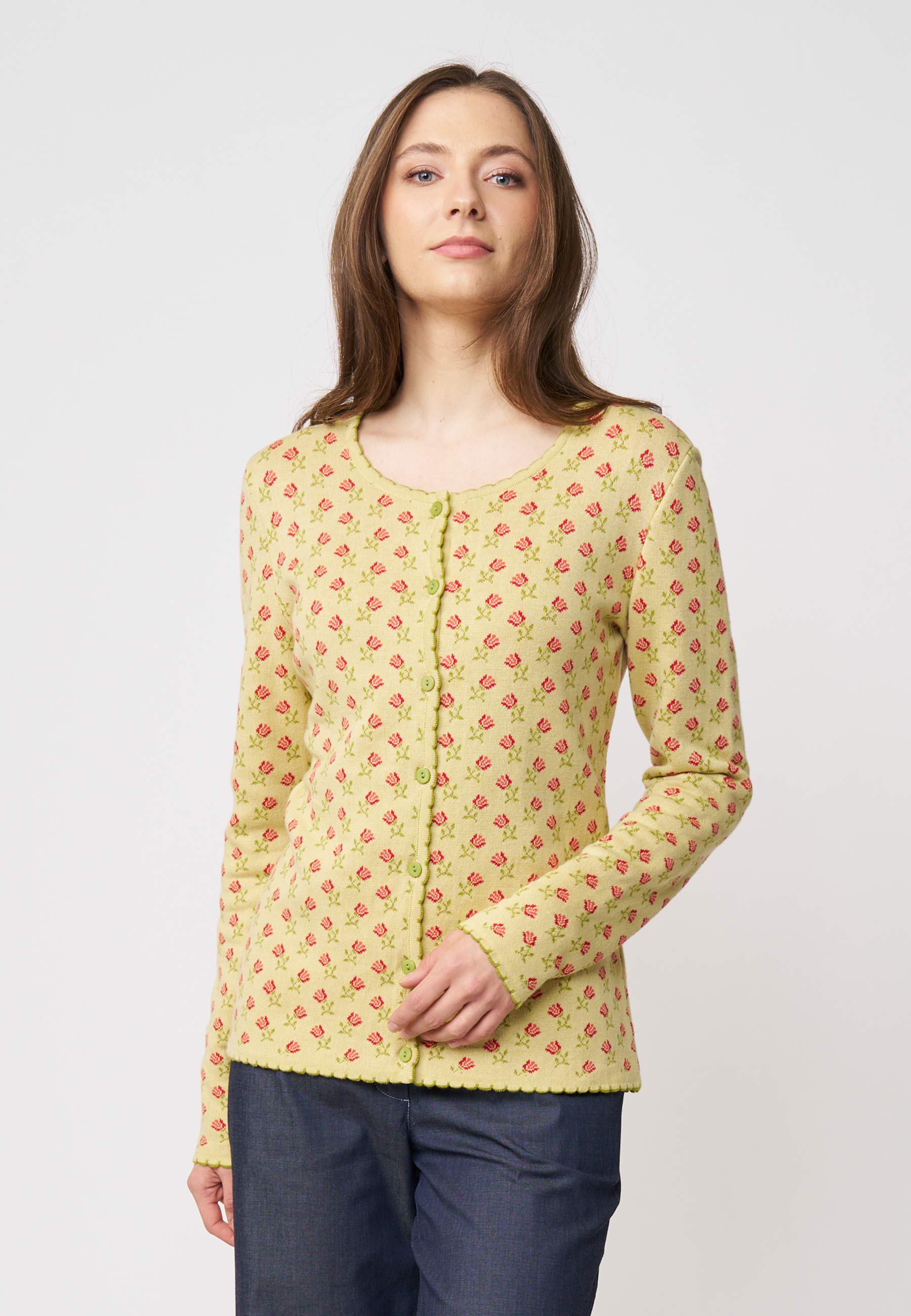 Frau trägt Strickjacke, Modell Lena, in hellem Gelb mit feinem rotem Blumenmuster und Knopfleiste