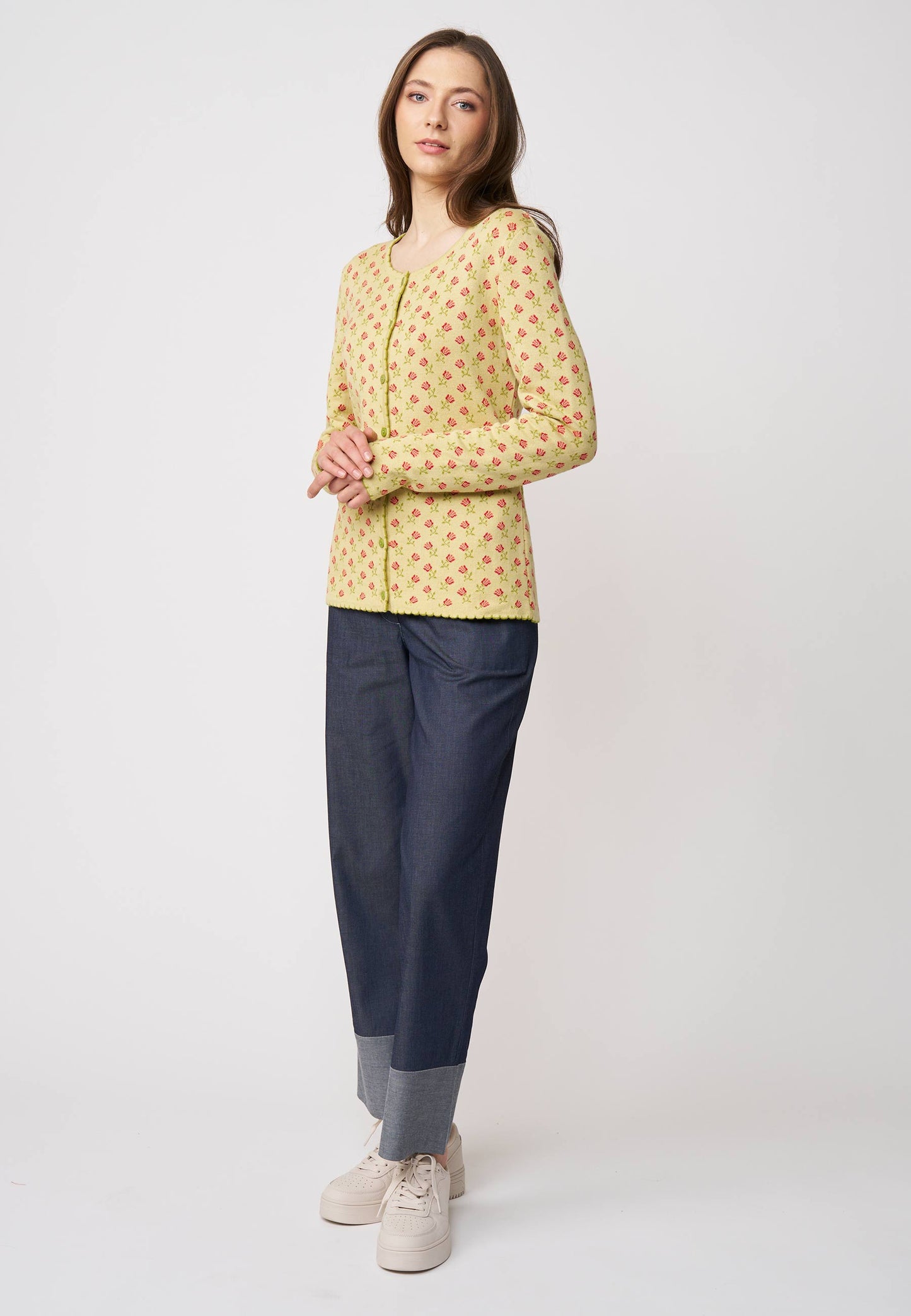 Frau trägt Strickjacke, Modell Lena, in hellem Gelb mit kleinem roten Muster vor hellem Hintergrund
