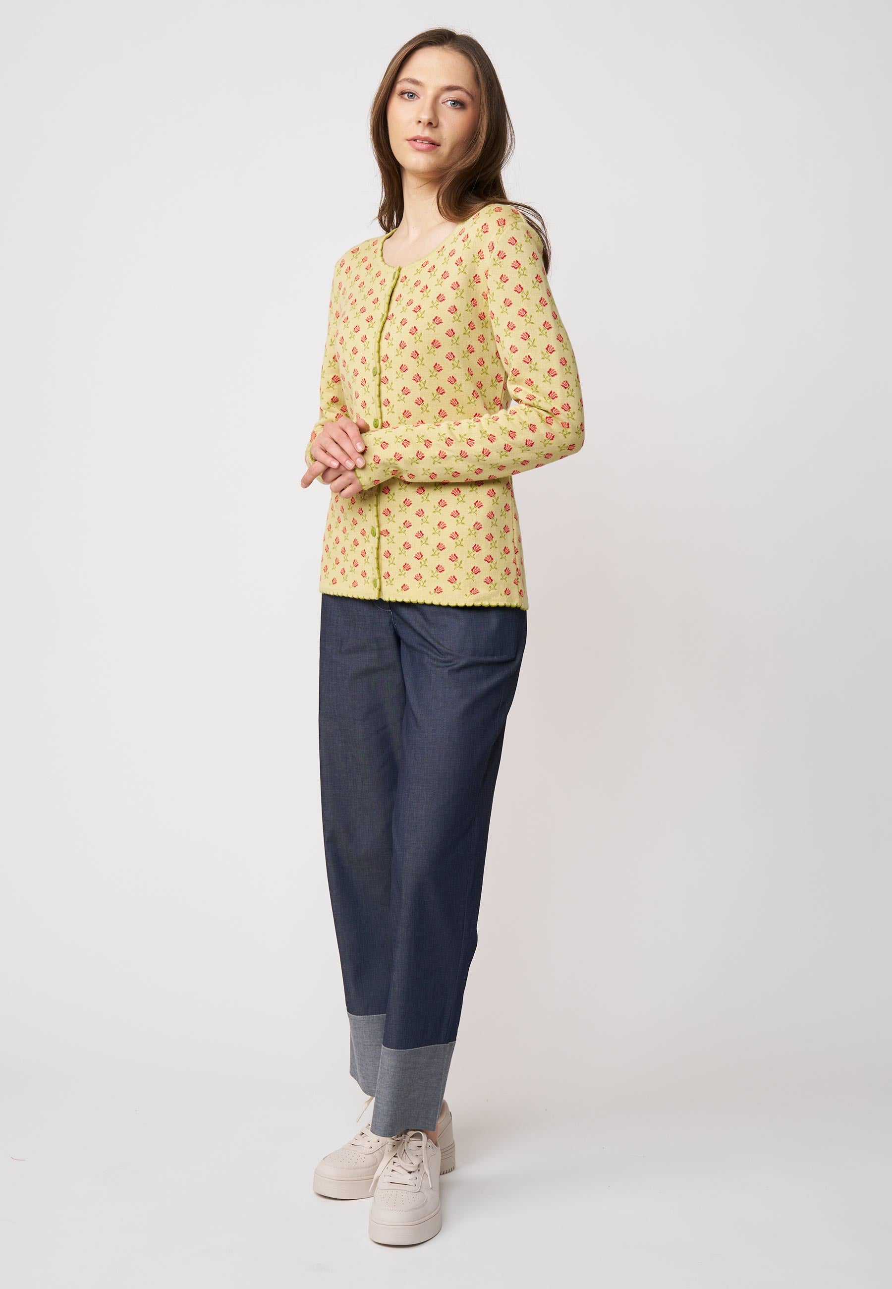 Frau trägt Strickjacke, Modell Lena, in hellem Gelb mit kleinem roten Muster vor hellem Hintergrund