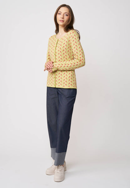Frau trägt Strickjacke, Modell Lena, in hellem Gelb mit kleinem roten Muster vor hellem Hintergrund
