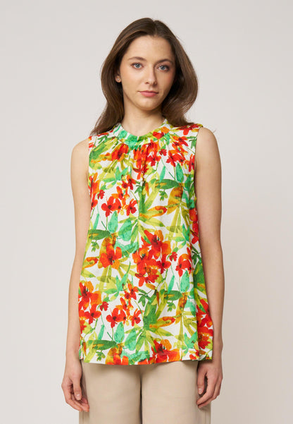 Frau trägt ärmelloses Top, Modell Ferra, mit buntem Blumenmuster in Rot und Grün vor hellem Hintergrund