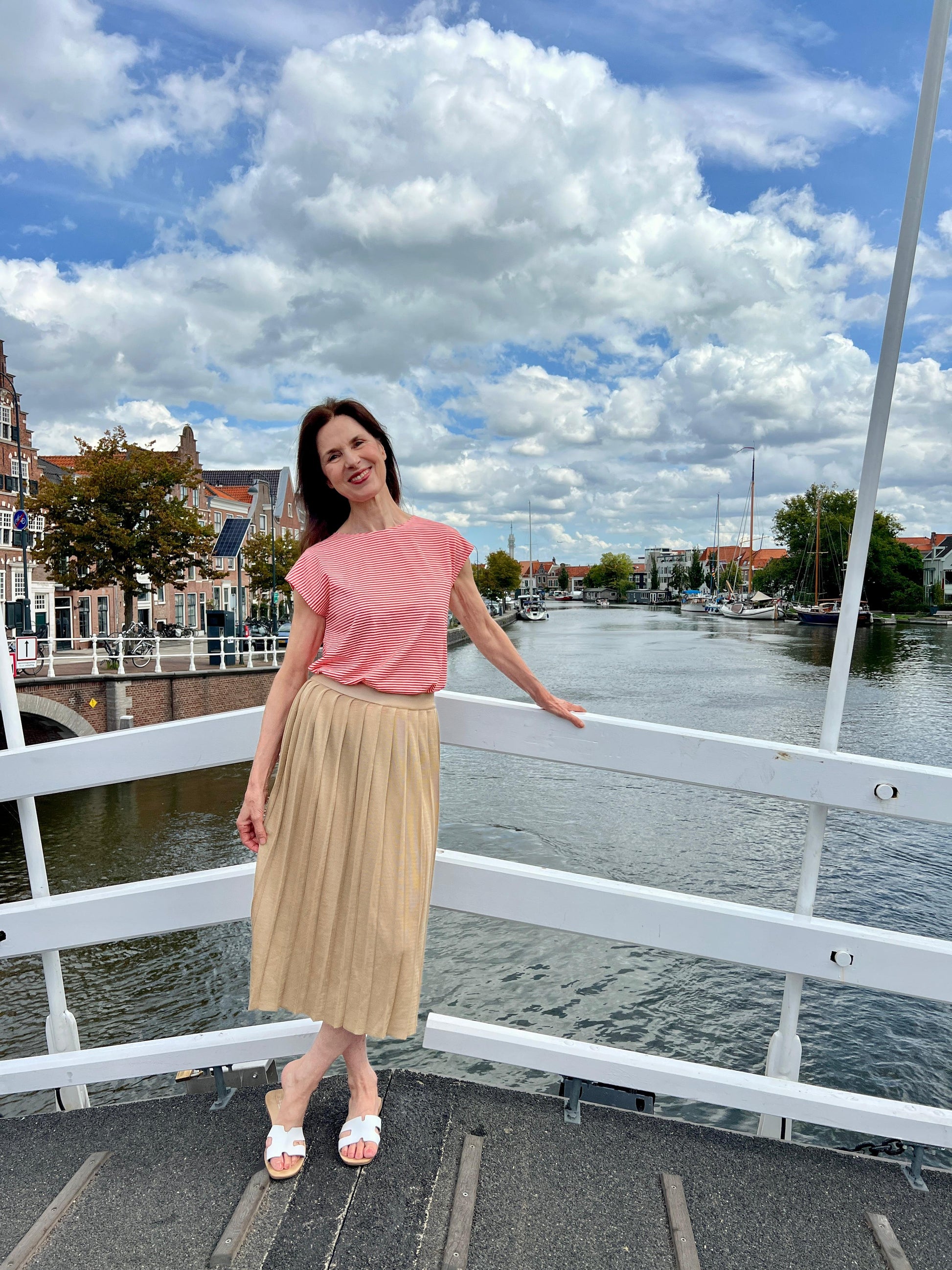 Rock, Modell Dajana in hellem Beige mit Faltenstruktur, stehend auf einer Brücke vor Wasser und Häuserkulisse