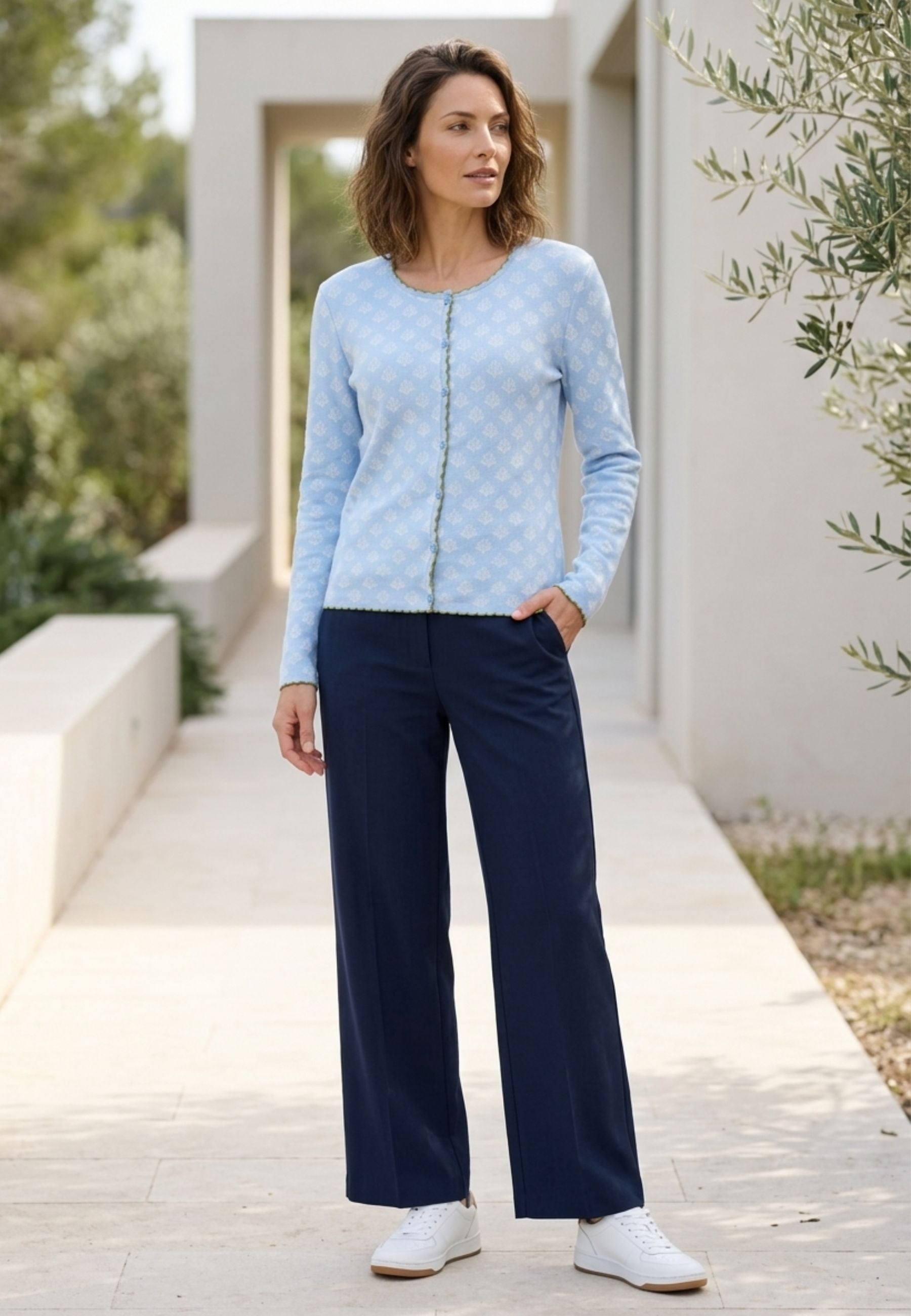 Strickjacke, Modell Lena in hellem Blau mit feinem Muster und zartem Kontrastbesatz, getragen bei sommerlichem Licht